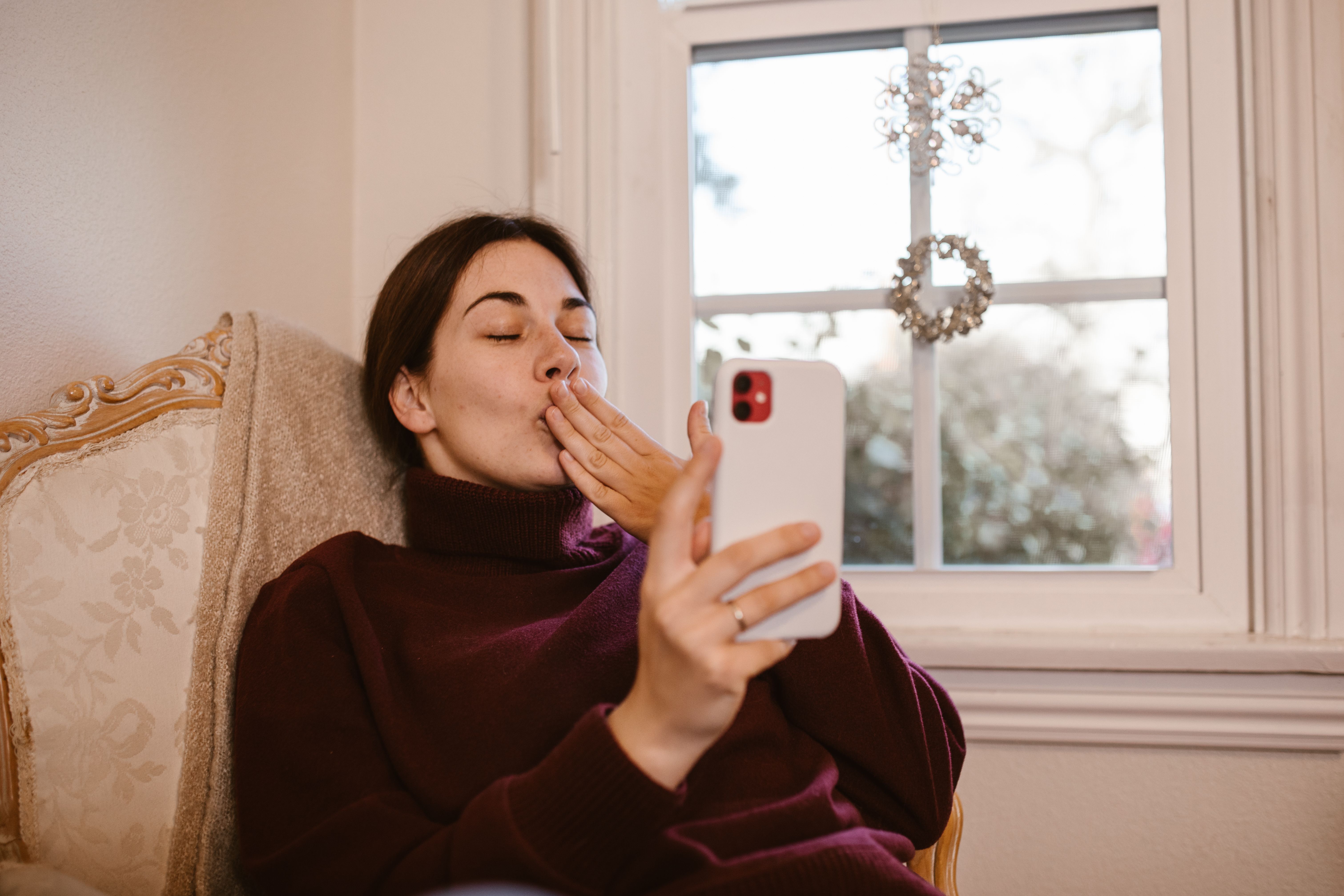 Woman blowing a kiss during a smartphone video call at home