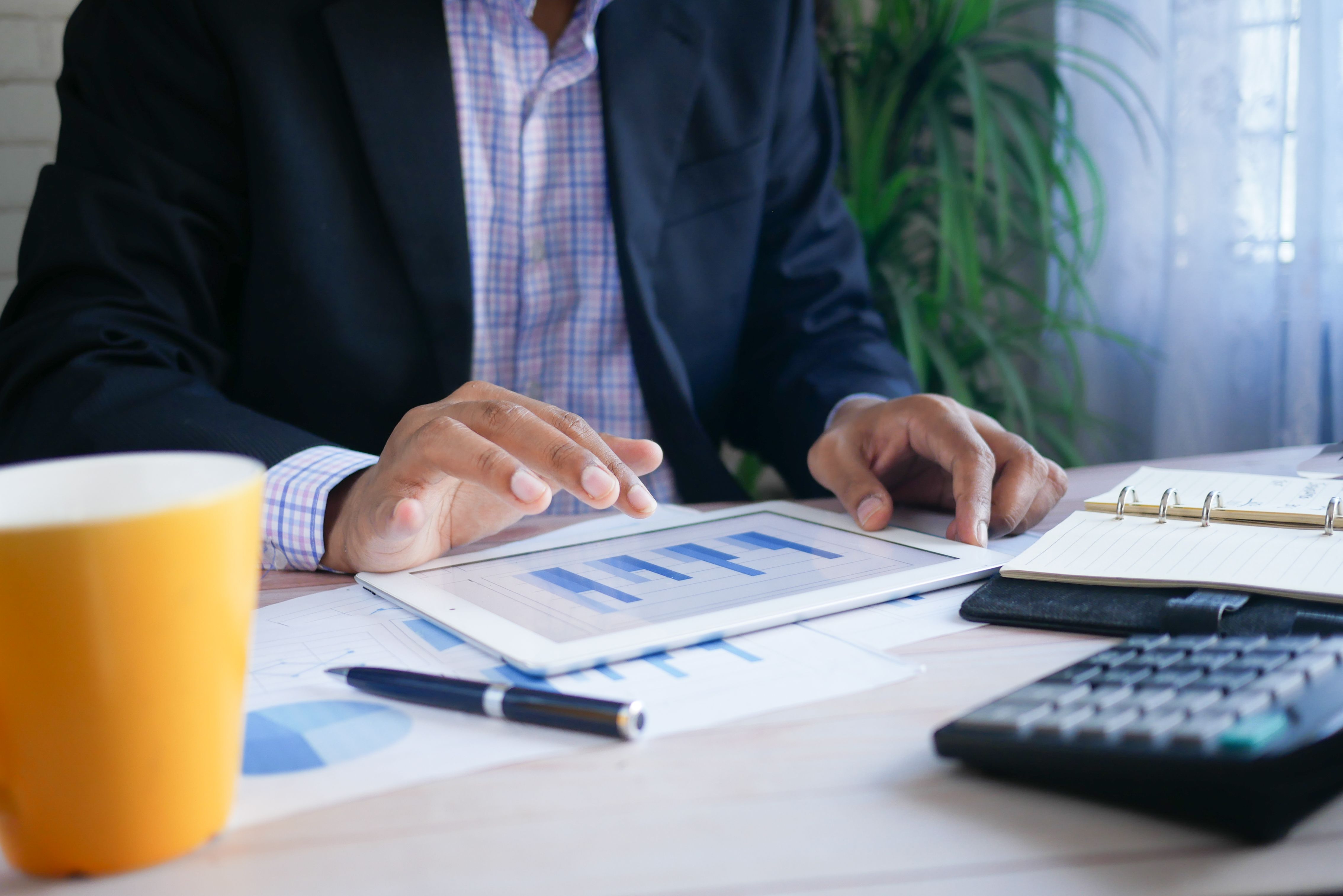 Man in office analyzing financial data on a digital tablet