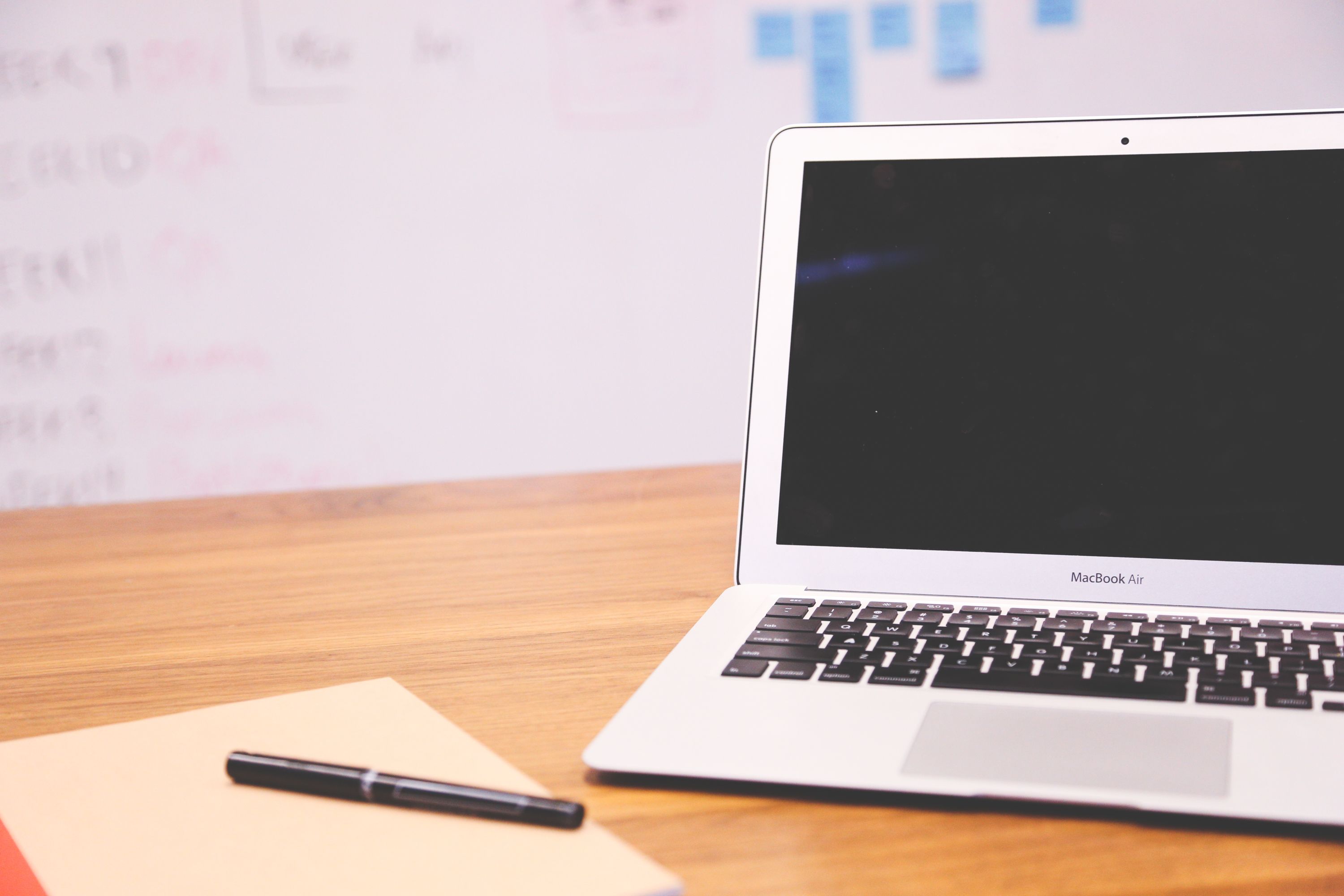 Sleek laptop on wooden desk with pen and notepad for a technology startup